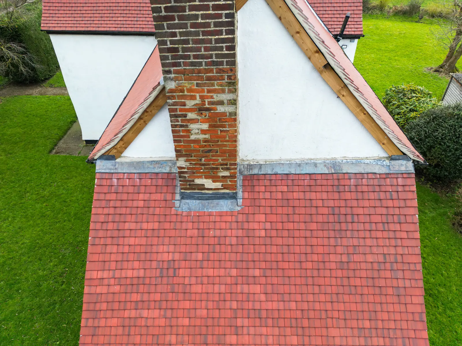 Red plain tile roof with a brick chimney