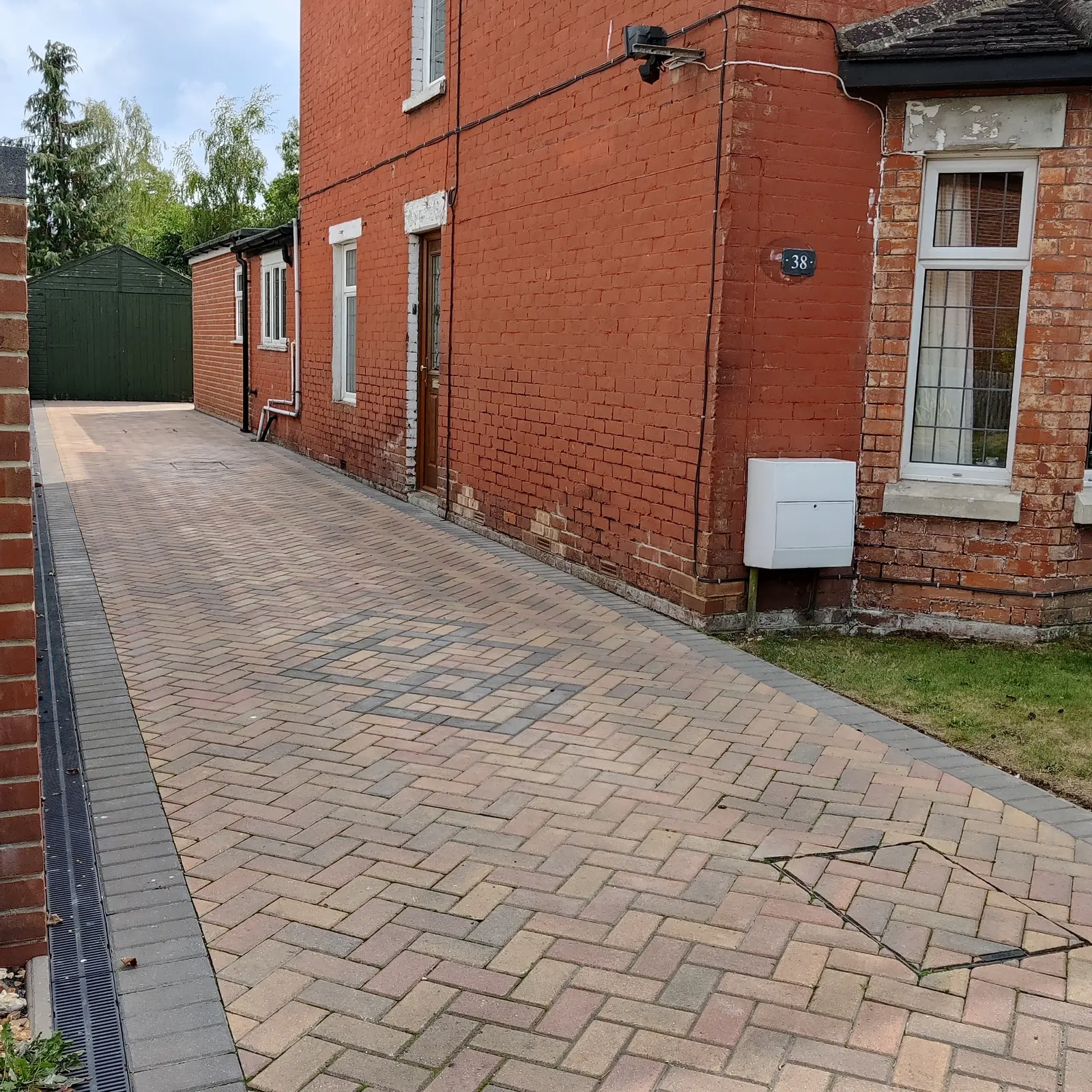Block paving driveway beside a red brick house